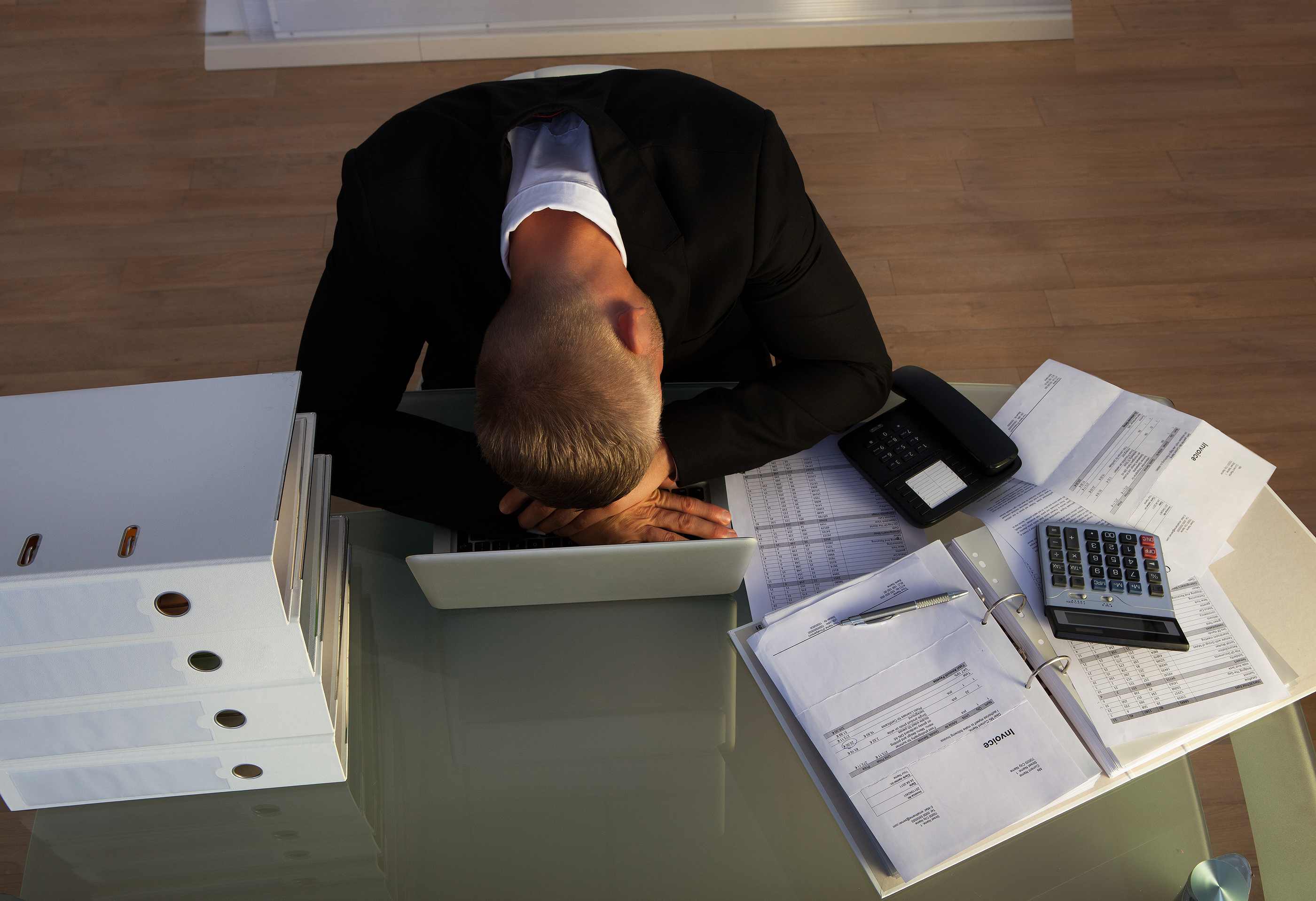 Exhausted businessman sleeping an a stack of files as he works late at the office during the evening as he tries to meet a deadline for the morning